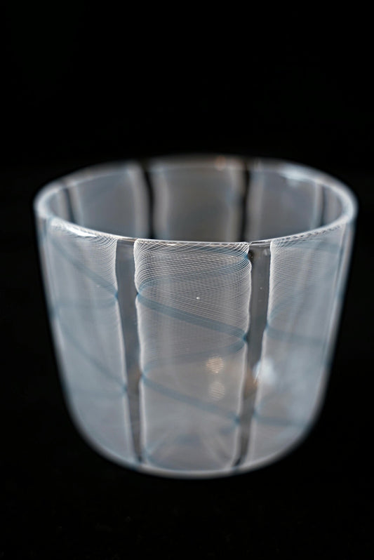 Clear glass cup wrapped in soft pale blue and white swirling stripes.
